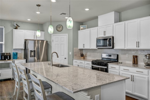 kitchen featuring visible vents, an island with sink, dark wood-style flooring, a sink, and stainless steel appliances