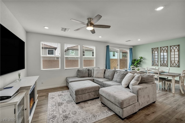 living room featuring a ceiling fan, wood finished floors, visible vents, baseboards, and recessed lighting