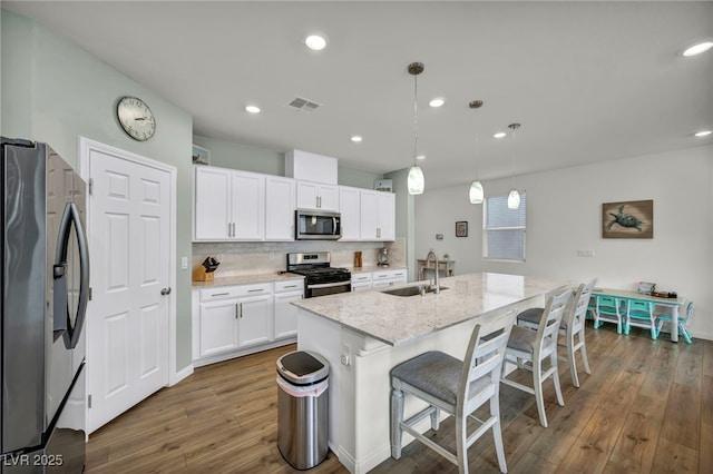 kitchen featuring visible vents, a sink, light stone counters, stainless steel appliances, and decorative backsplash