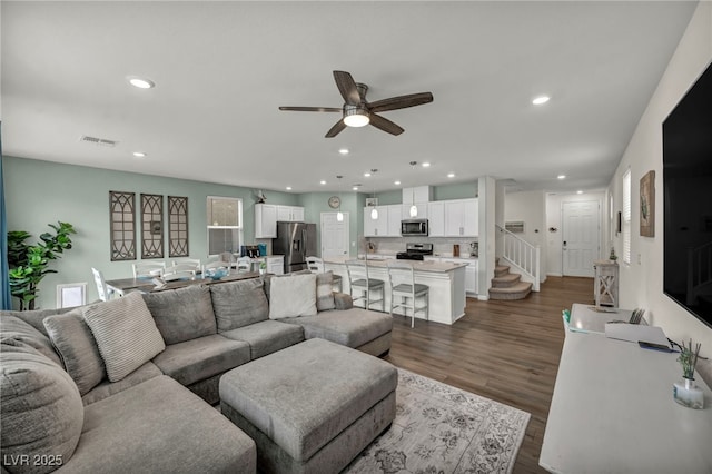 living area featuring visible vents, a ceiling fan, dark wood finished floors, recessed lighting, and stairway