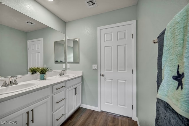 bathroom featuring double vanity, wood finished floors, visible vents, and a sink