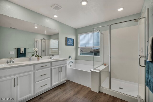 bathroom with a sink, visible vents, wood finished floors, and a shower stall