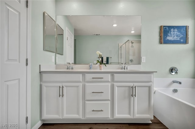 full bathroom with a sink, a garden tub, a shower stall, and double vanity
