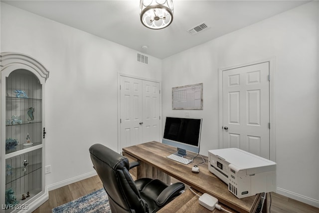 office area featuring visible vents, baseboards, and wood finished floors