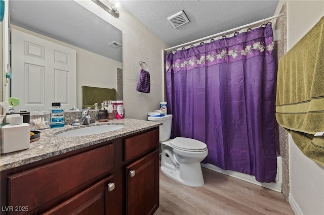 bathroom featuring visible vents, toilet, wood finished floors, and a textured ceiling