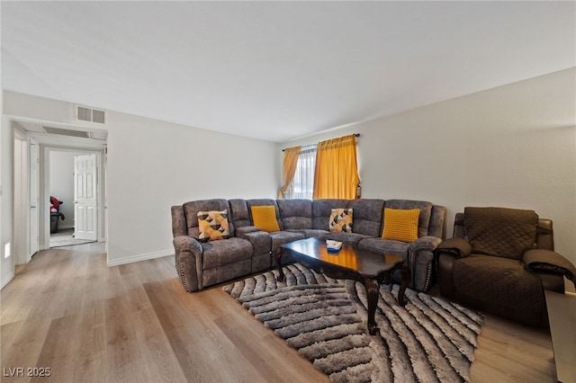 living room with visible vents, baseboards, and light wood-style floors