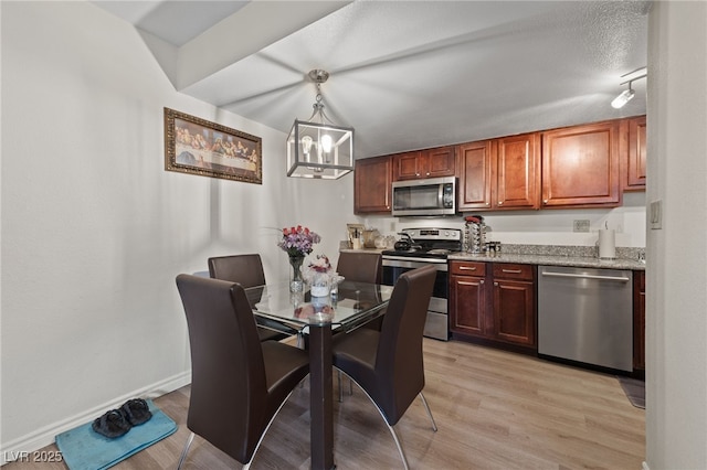 kitchen featuring baseboards, appliances with stainless steel finishes, light wood-style floors, hanging light fixtures, and a notable chandelier