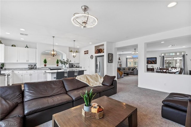 carpeted living area with a notable chandelier, visible vents, and recessed lighting