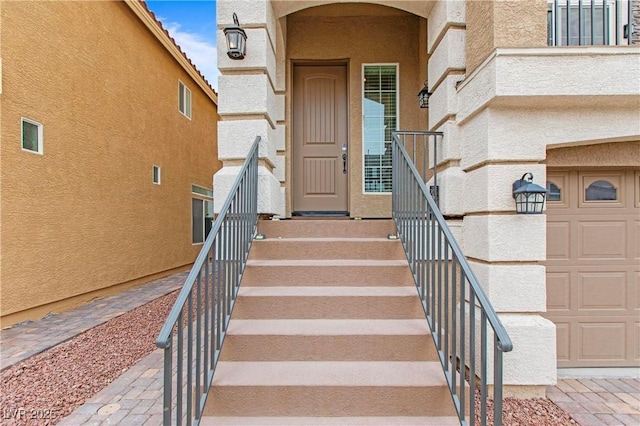 property entrance featuring a garage and stucco siding