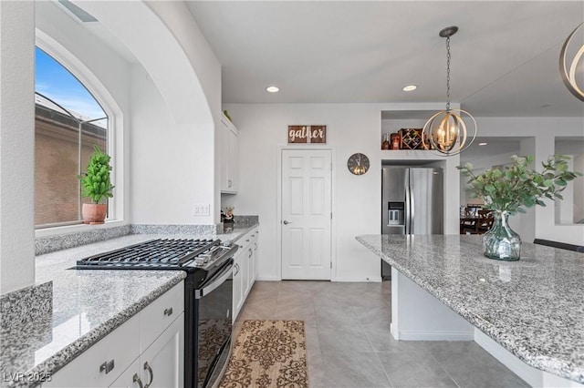 kitchen with decorative light fixtures, light stone counters, an inviting chandelier, white cabinets, and gas range