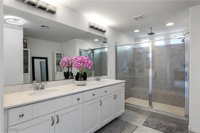 bathroom with visible vents, a stall shower, and a sink