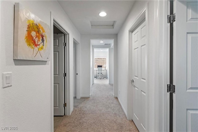 corridor with light carpet, visible vents, and baseboards