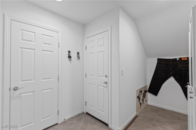 interior space with light tile patterned flooring, baseboards, and vaulted ceiling