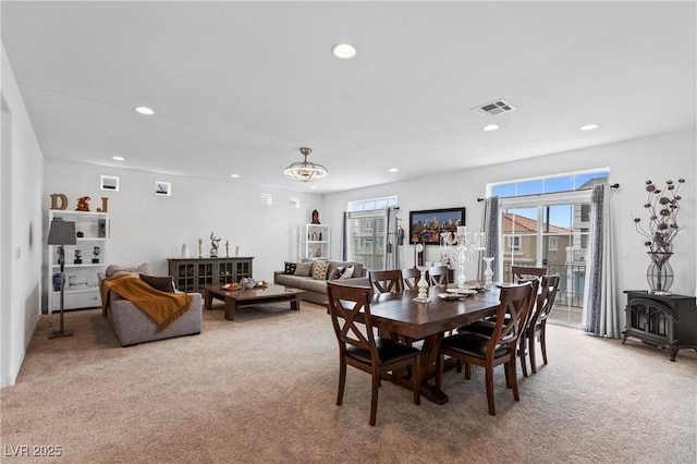 dining area featuring carpet flooring, recessed lighting, a wood stove, and visible vents