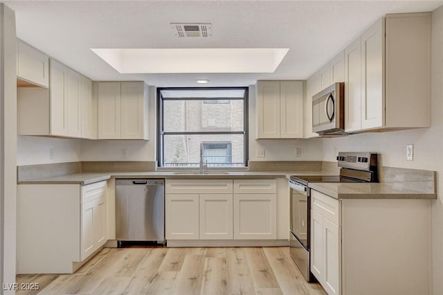 kitchen featuring a sink, visible vents, a raised ceiling, and appliances with stainless steel finishes