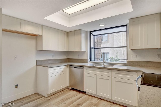 kitchen featuring stainless steel dishwasher, light countertops, light wood-style flooring, and a sink