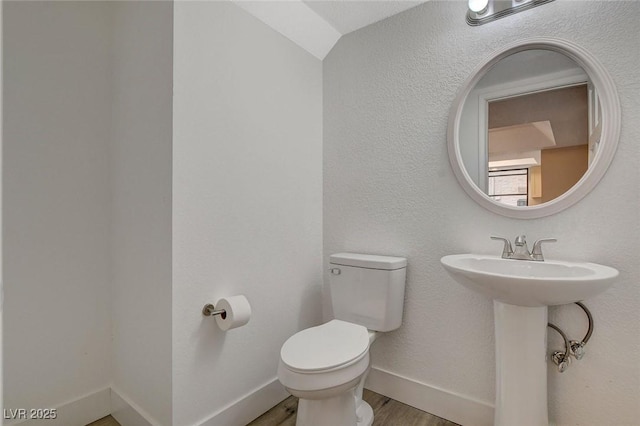 bathroom featuring a sink, toilet, baseboards, and wood finished floors