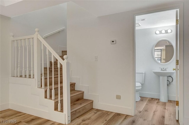 stairway featuring visible vents, wood finished floors, and baseboards