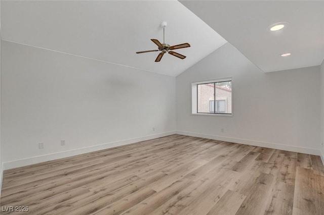 spare room with vaulted ceiling, light wood-style floors, baseboards, and ceiling fan