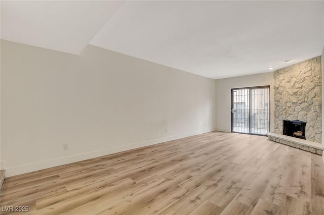 unfurnished living room featuring a fireplace, light wood-style floors, and baseboards