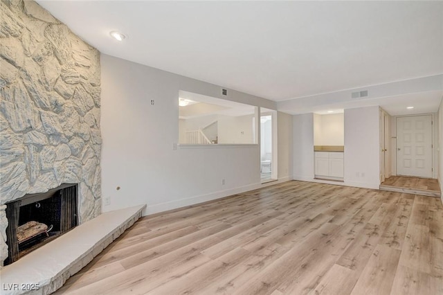 unfurnished living room featuring visible vents, wood finished floors, a fireplace, baseboards, and stairs