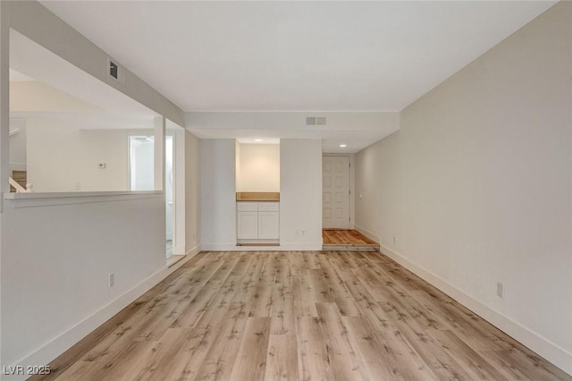 spare room featuring light wood finished floors, visible vents, and baseboards