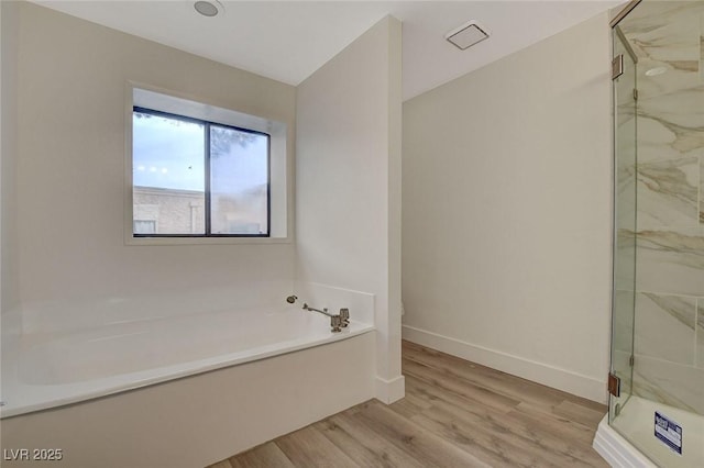 full bathroom featuring a marble finish shower, baseboards, a garden tub, and wood finished floors