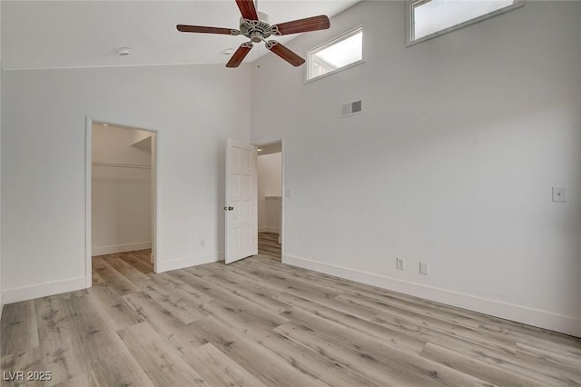 unfurnished bedroom featuring baseboards, visible vents, light wood finished floors, a spacious closet, and a closet