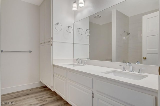 full bathroom with walk in shower, wood finished floors, baseboards, and a sink