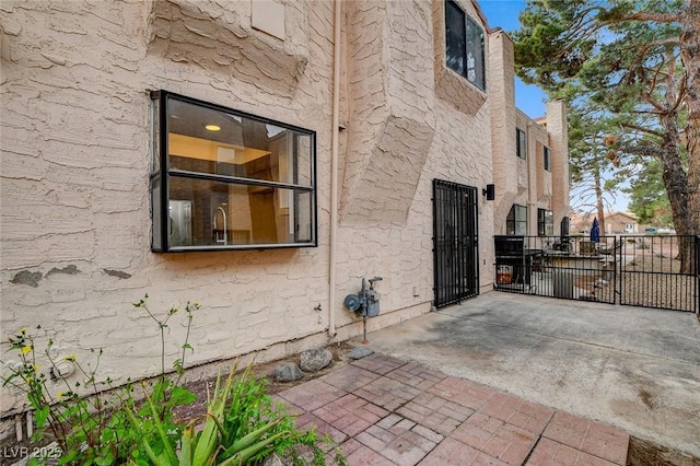 view of home's exterior featuring a gate, stucco siding, a patio, and fence