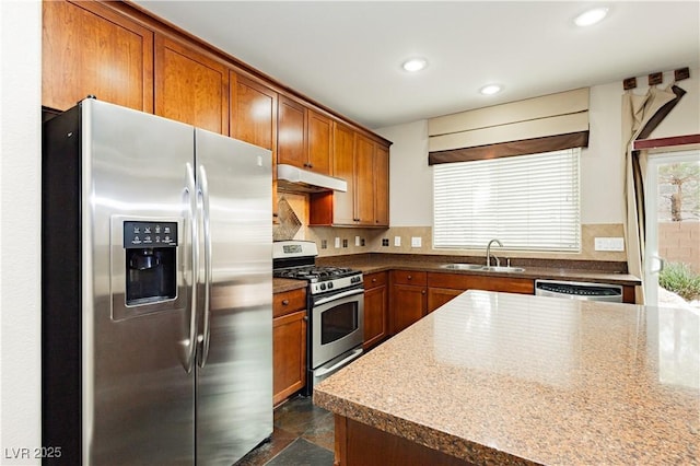 kitchen with under cabinet range hood, recessed lighting, brown cabinets, stainless steel appliances, and a sink