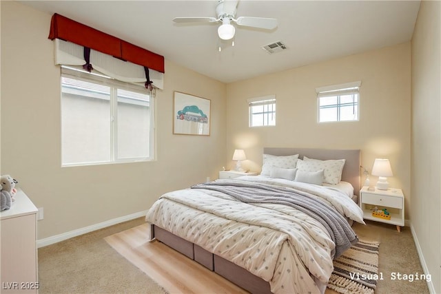 carpeted bedroom with visible vents, a ceiling fan, and baseboards