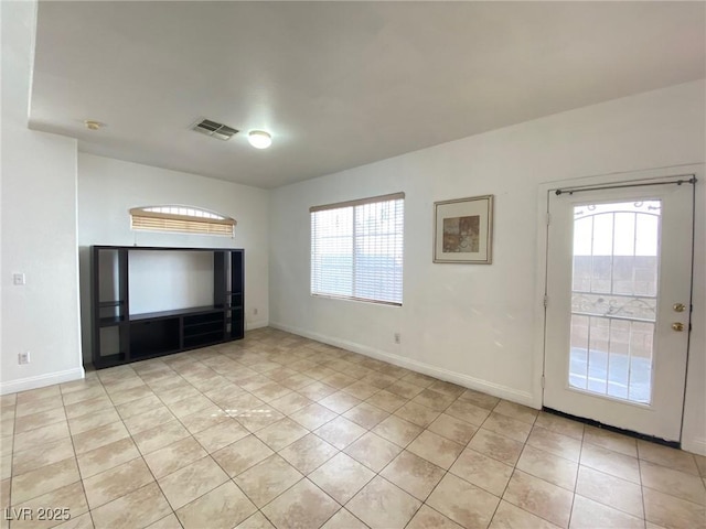 unfurnished living room featuring light tile patterned floors, visible vents, plenty of natural light, and baseboards