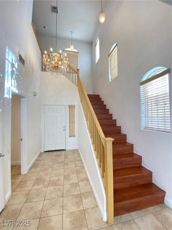 entryway with light tile patterned floors, baseboards, visible vents, stairs, and a notable chandelier