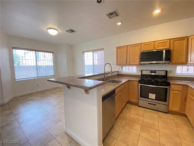 kitchen with visible vents, light tile patterned floors, appliances with stainless steel finishes, a peninsula, and a sink