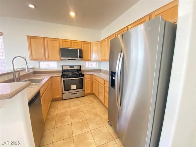 kitchen featuring light brown cabinetry, light tile patterned floors, a peninsula, stainless steel appliances, and a sink