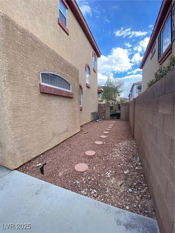 view of side of property featuring a gate, fence, and stucco siding