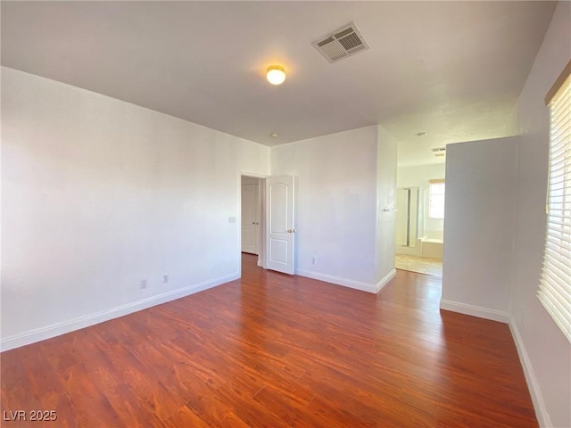 unfurnished room featuring wood finished floors, visible vents, and baseboards