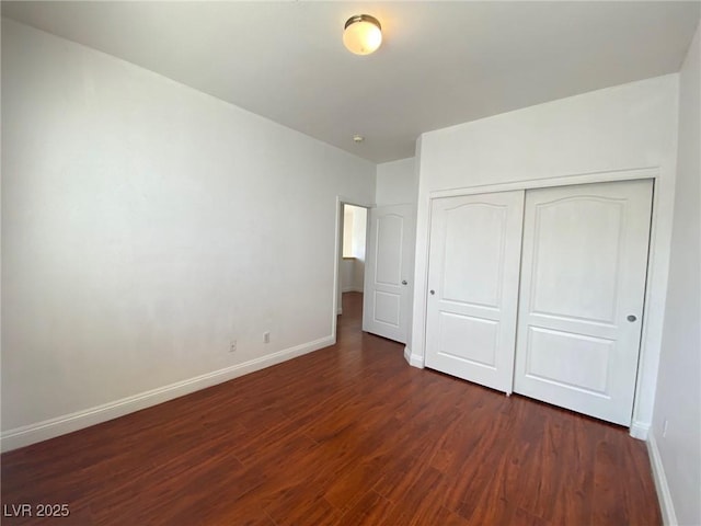 unfurnished bedroom featuring a closet, baseboards, and dark wood-style floors