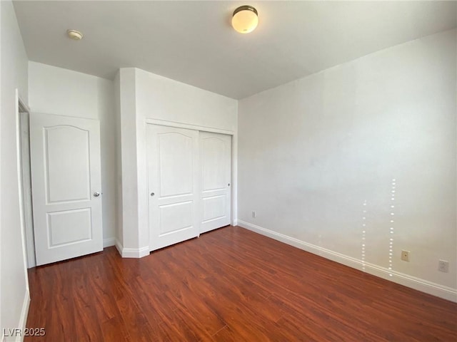 unfurnished bedroom featuring a closet, baseboards, and wood finished floors