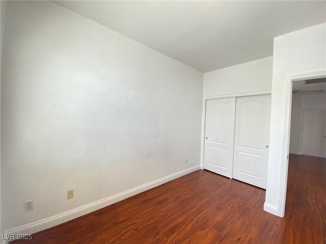 unfurnished bedroom with dark wood-type flooring, baseboards, and a closet