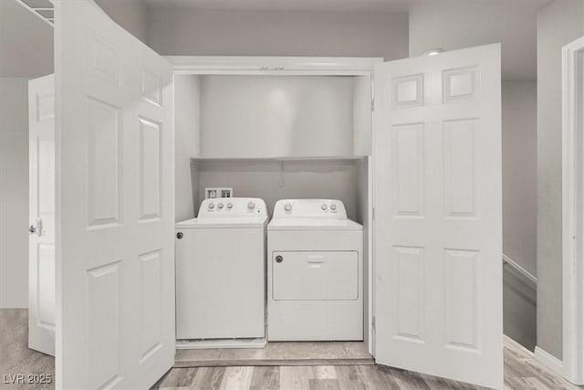 clothes washing area featuring laundry area, light wood-style flooring, and washer and clothes dryer