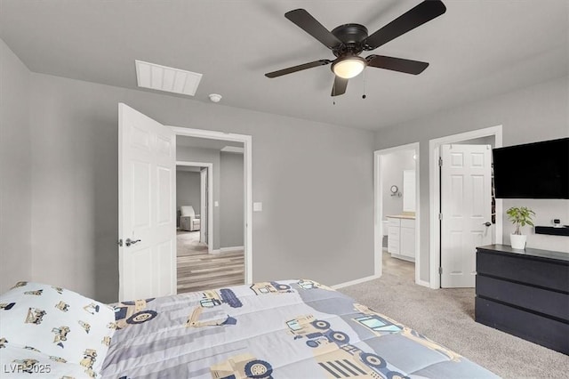 bedroom featuring visible vents, baseboards, light colored carpet, ensuite bath, and a ceiling fan