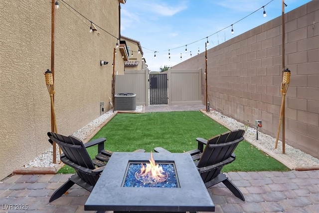 view of yard with a gate, cooling unit, an outdoor fire pit, a fenced backyard, and a patio area