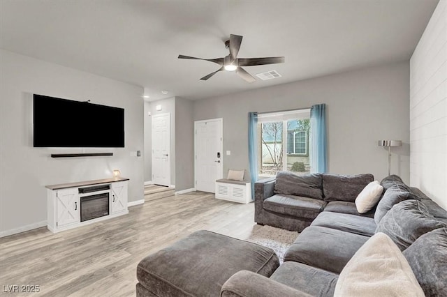 living area with visible vents, baseboards, light wood-type flooring, and a ceiling fan