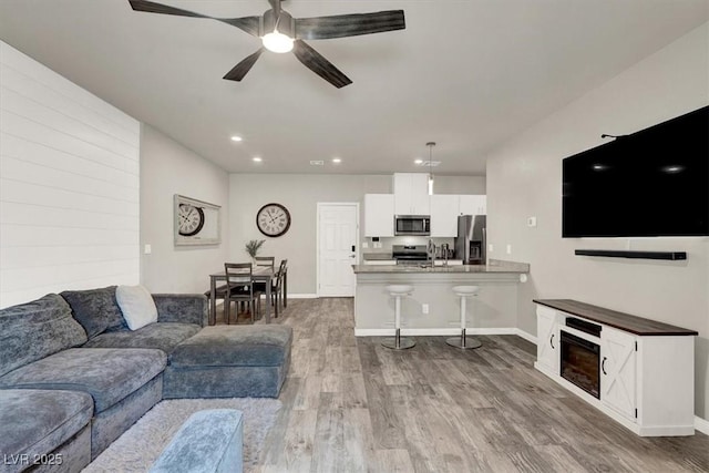 living area featuring recessed lighting, baseboards, ceiling fan, and wood finished floors