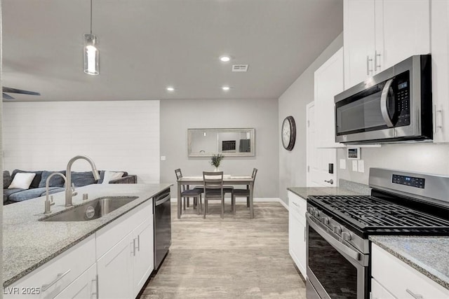 kitchen with visible vents, a sink, light stone counters, appliances with stainless steel finishes, and white cabinets