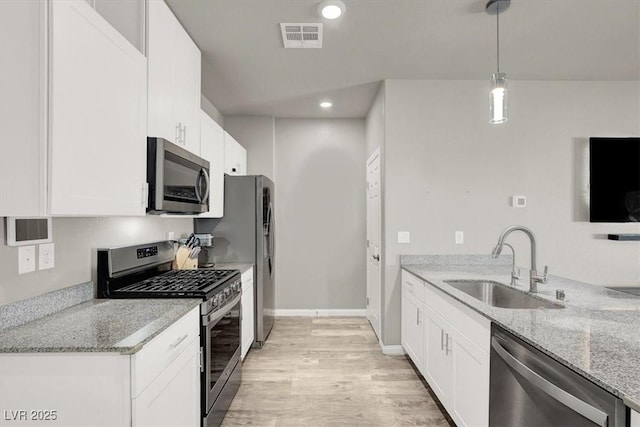 kitchen with visible vents, a sink, appliances with stainless steel finishes, white cabinets, and light stone countertops