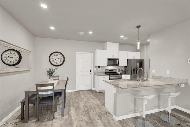 kitchen with white cabinetry, a peninsula, appliances with stainless steel finishes, and a sink