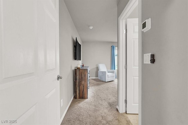 hallway featuring baseboards and light colored carpet